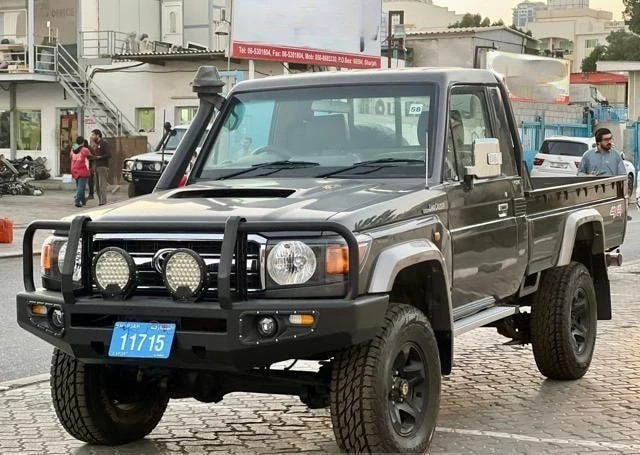 alt text:  A close-up view of the front of a gray 2014 Toyota Land Cruiser single-cab pickup truck, showcasing its grill and headlights.