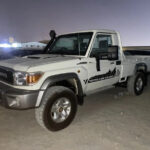 alt text: A white 2013 Toyota Land Cruiser single-cab pickup truck parked on a paved surface.