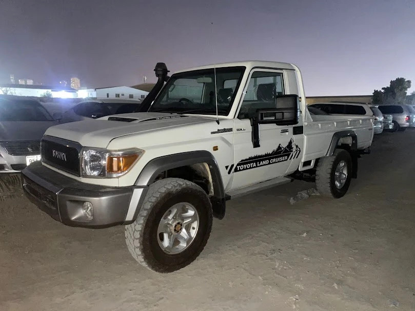 alt text: A white 2013 Toyota Land Cruiser single-cab pickup truck parked on a paved surface.