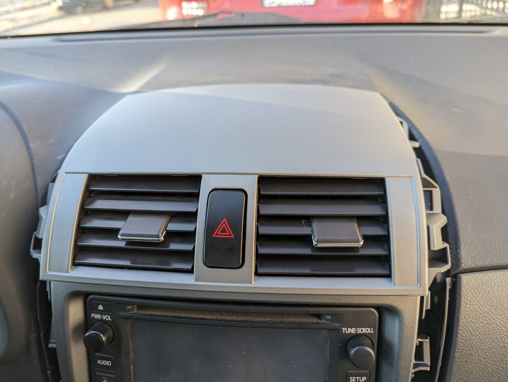 Replacement air vent assembly aligned for installation in a 2013 Toyota Corolla center console.