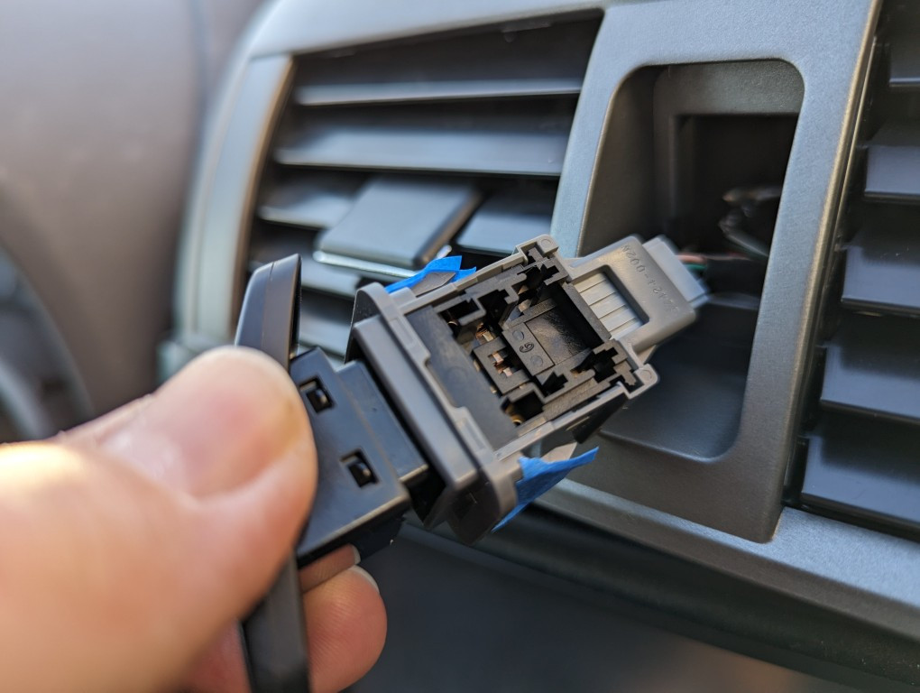 Closer view of masking tape reinforcement on the caution lights switch for a 2013 Toyota Corolla vent install.