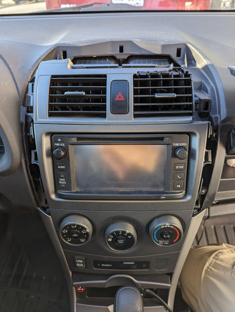 Side covers of a 2013 Toyota Corolla center console removed to access air vent assembly.