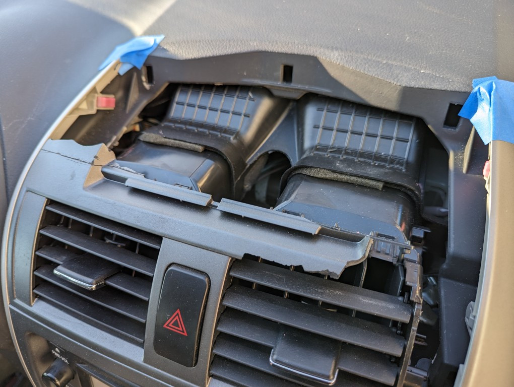 Close-up of the damaged air vent assembly in a 2013 Toyota Corolla before removal.