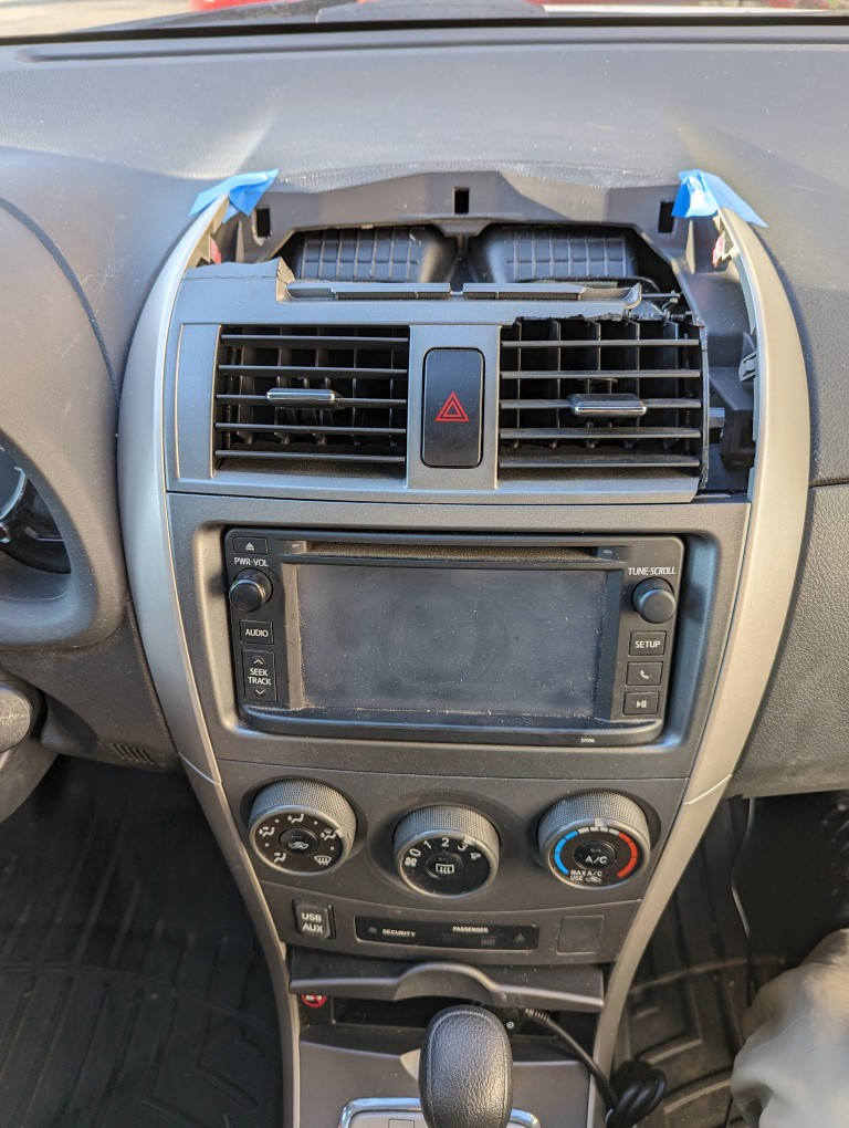 2013 Toyota Corolla's dashboard with the top of the center console air vent removed after damage.