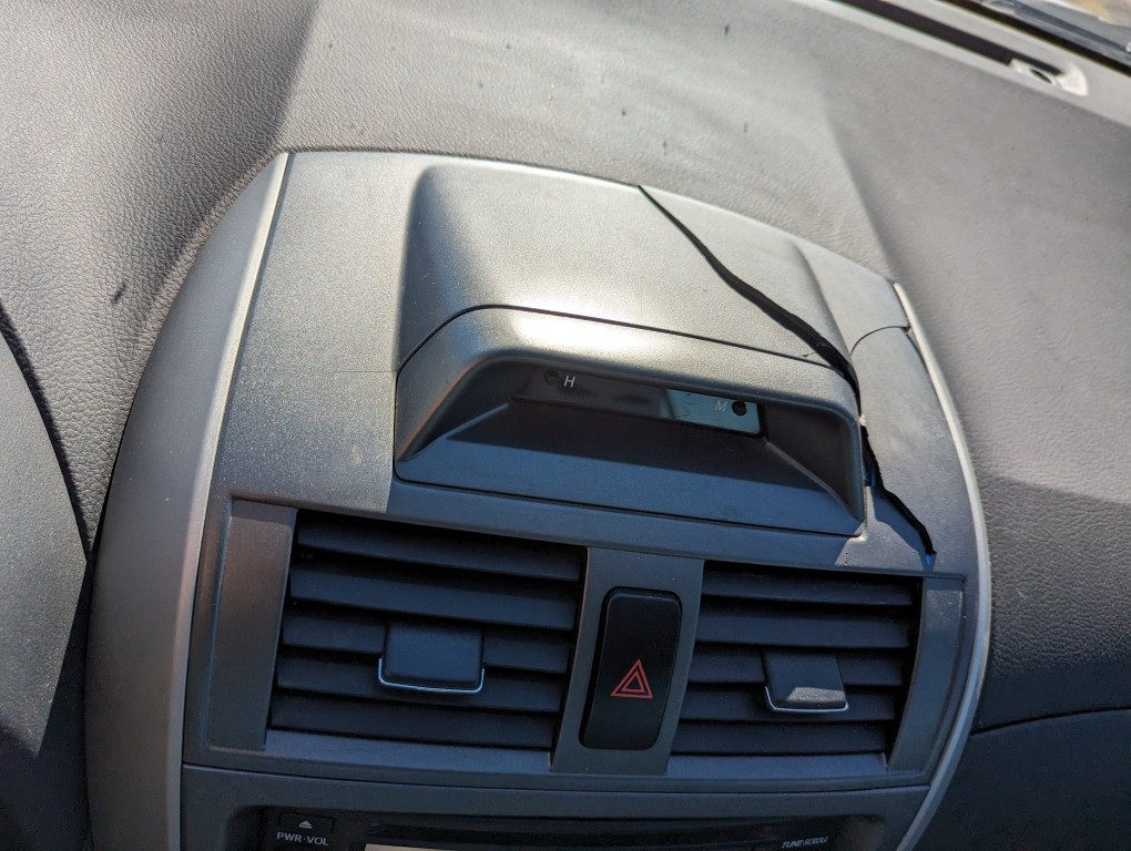 Reassembled broken air vent of a 2013 Toyota Corolla showing cracked plastic pieces.