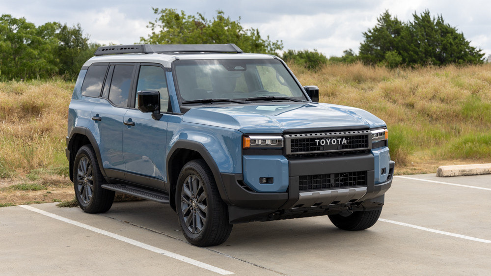 Front three-quarter view of the 2024 Toyota Land Cruiser Premium in Smoky Blue, highlighting its modern design, alloy wheels, and overall premium SUV appearance.