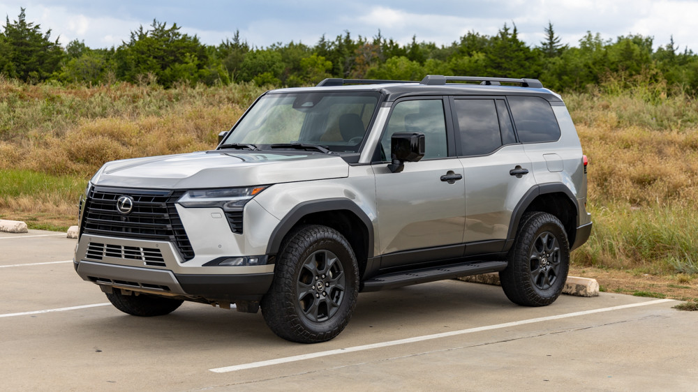 Side profile of the 2024 Lexus GX 550 Overtrail in Atomic Silver, highlighting its robust stance, off-road tires, and advanced suspension system designed for challenging terrains.