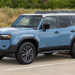 Front view of the 2024 Toyota Land Cruiser Premium in Smoky Blue, showcasing its rectangular headlights and rugged design, ideal for off-road enthusiasts and daily commutes.