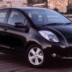 Front three quarter view of a 2007 Toyota Yaris hatchback in silver, highlighting its compact size.