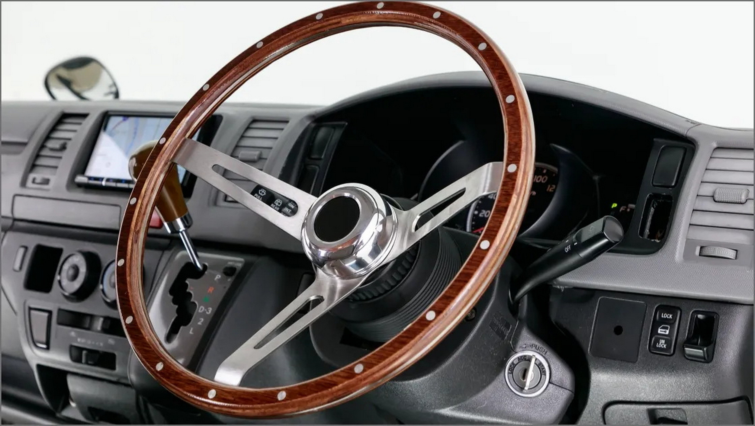 Interior view of a Toyota HiAce Vanace showcasing retro seat covers and wooden steering wheel.