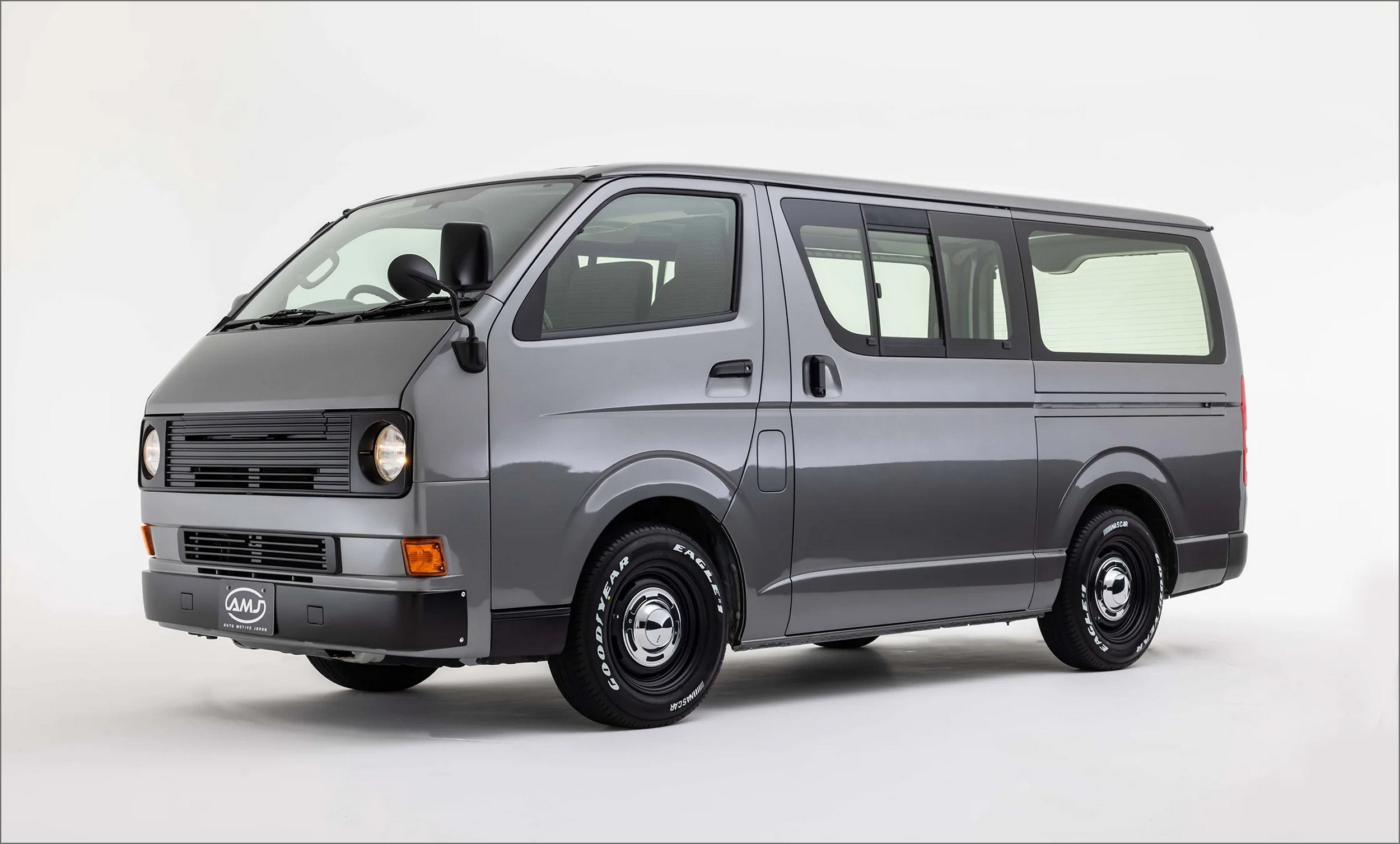 Front view of a beige Toyota HiAce Vanace Type 1 with dual round headlights, retro bumper, and chrome wheels.