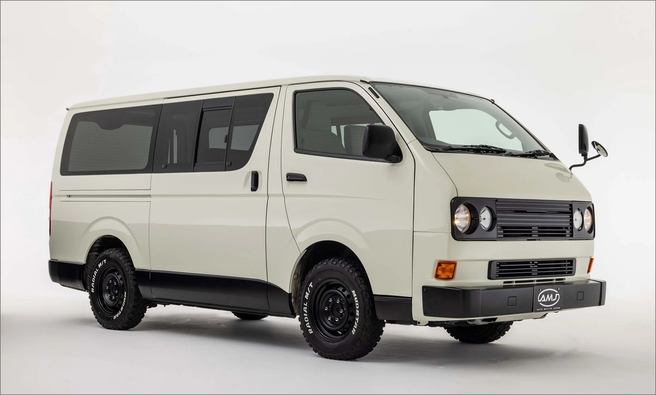 Angled front view of a white Toyota HiAce Vanace Type 2 with quad headlights, black rocker panels, and chrome wheels.