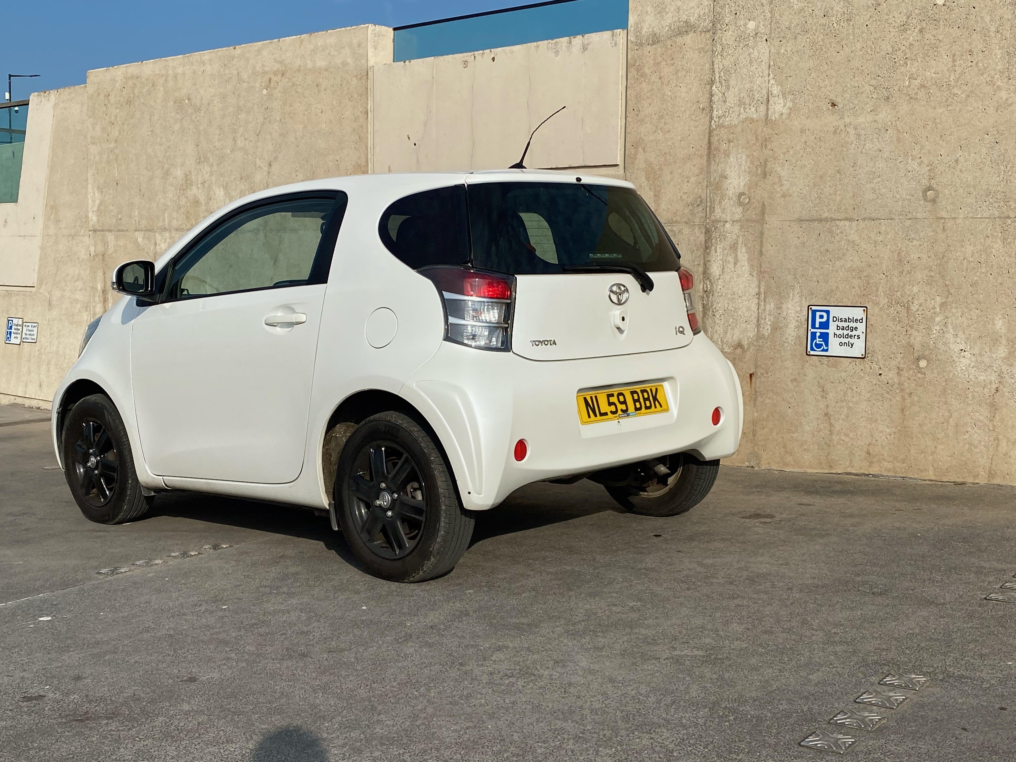 Front view of a white Toyota iQ parked on a street.