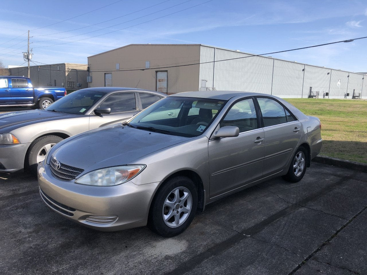 Front side view of a 2003 Toyota Camry LE, parked in a lot, showcasing its clean lines and original factory wheels.