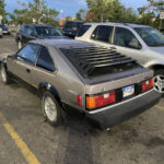 Front quarter view of a red 1985 Toyota Celica GT-S parked on a city street, showcasing its pop-up headlights and sporty design.