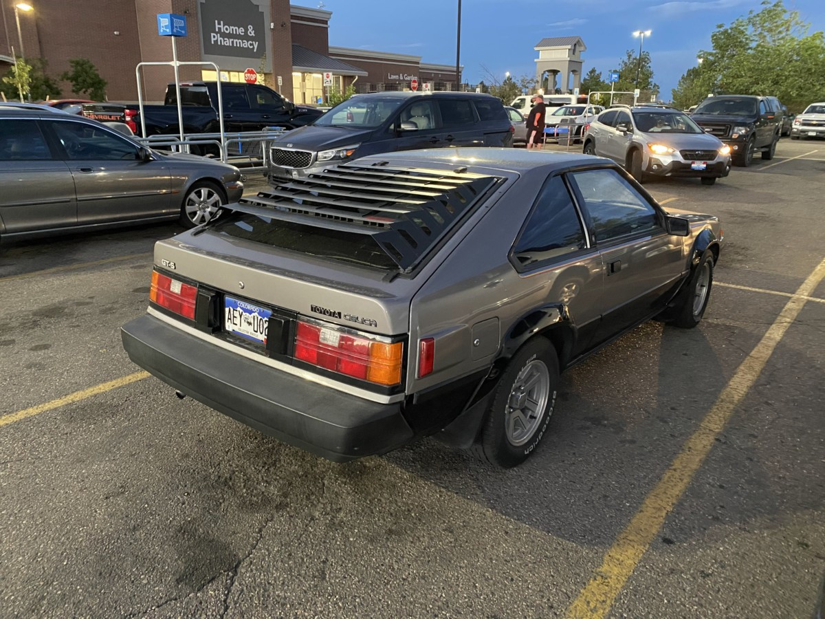 Full car shot of a red 1985 Toyota Celica GT-S parked outdoors, capturing its overall design and classic appeal.