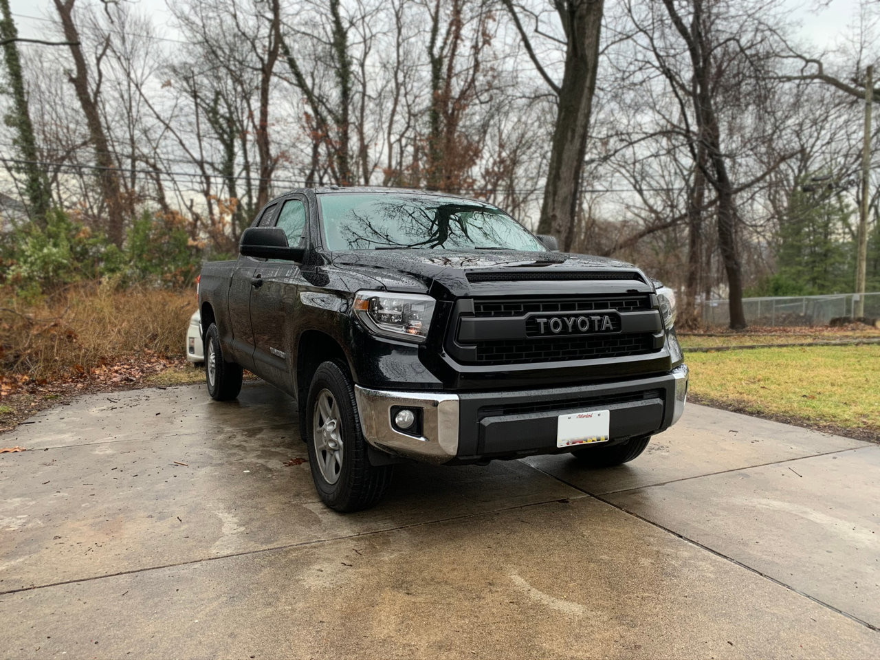 The black Toyota Tundra from a side angle, highlighting its lifted suspension and larger off-road tires.