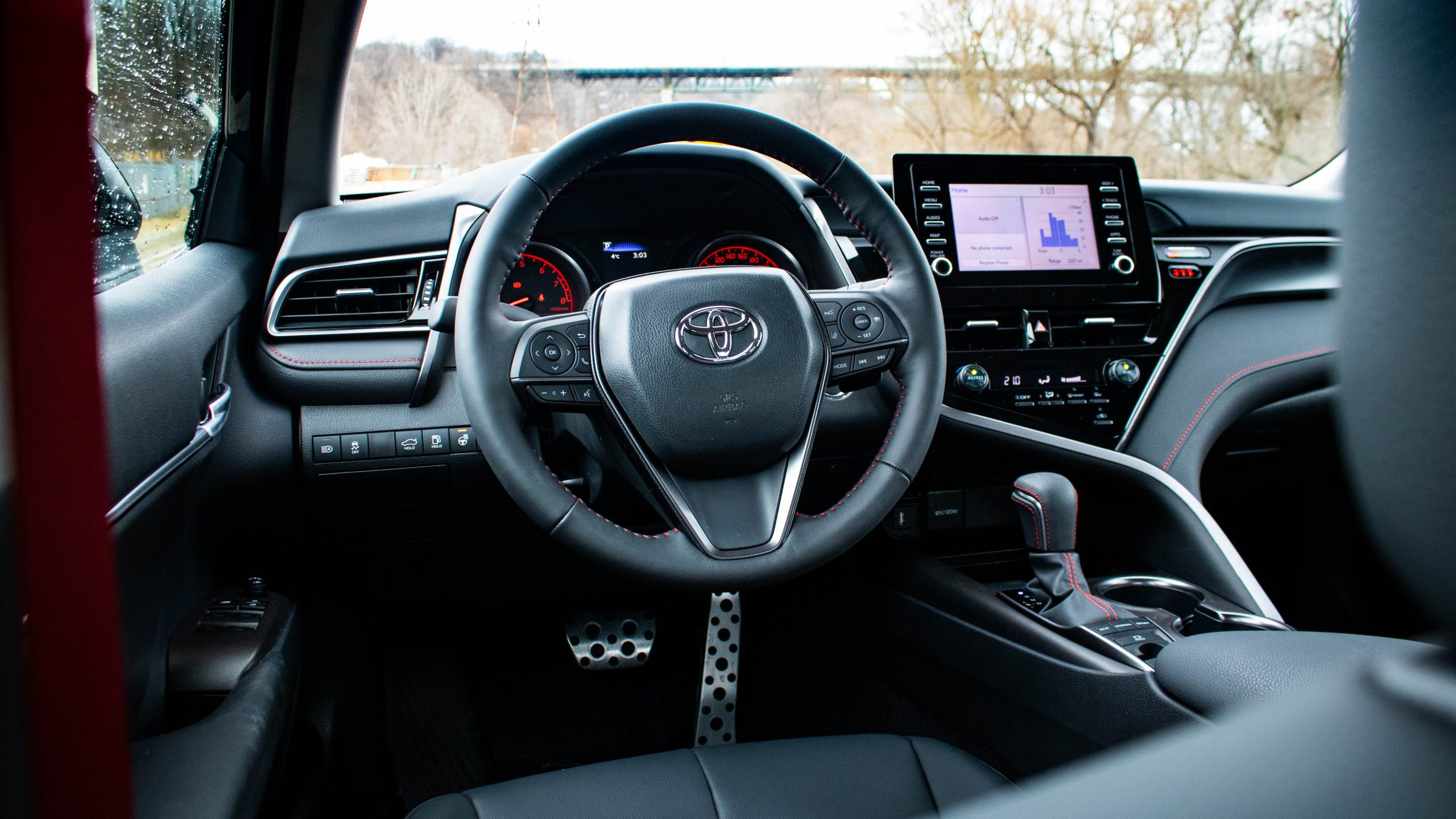 Side profile of the 2024 Toyota Camry TRD V6, highlighting the red TRD side skirts, black wheels, and sporty stance.