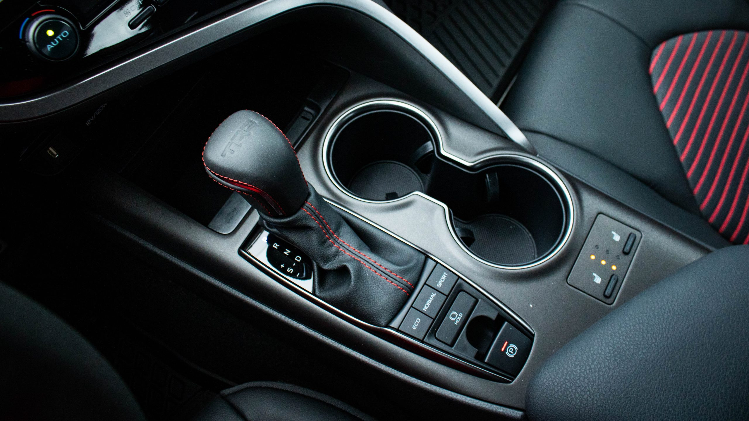 Front three-quarter view of the 2024 Toyota Camry TRD V6, emphasizing the black TRD wheels and red brake calipers.