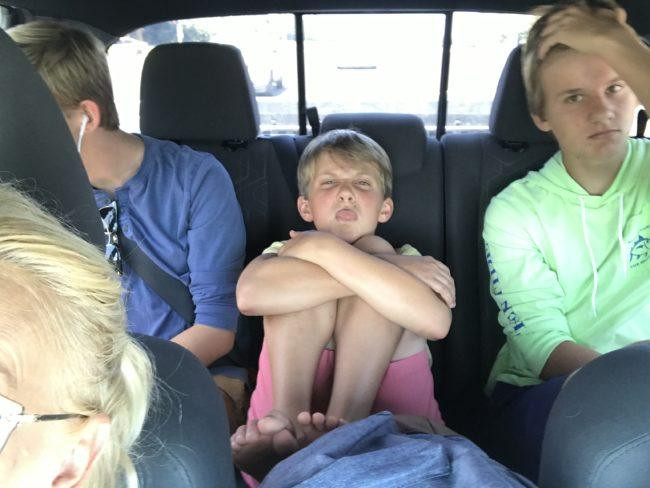 Three boys sitting in the back of a Toyota Tacoma truck.