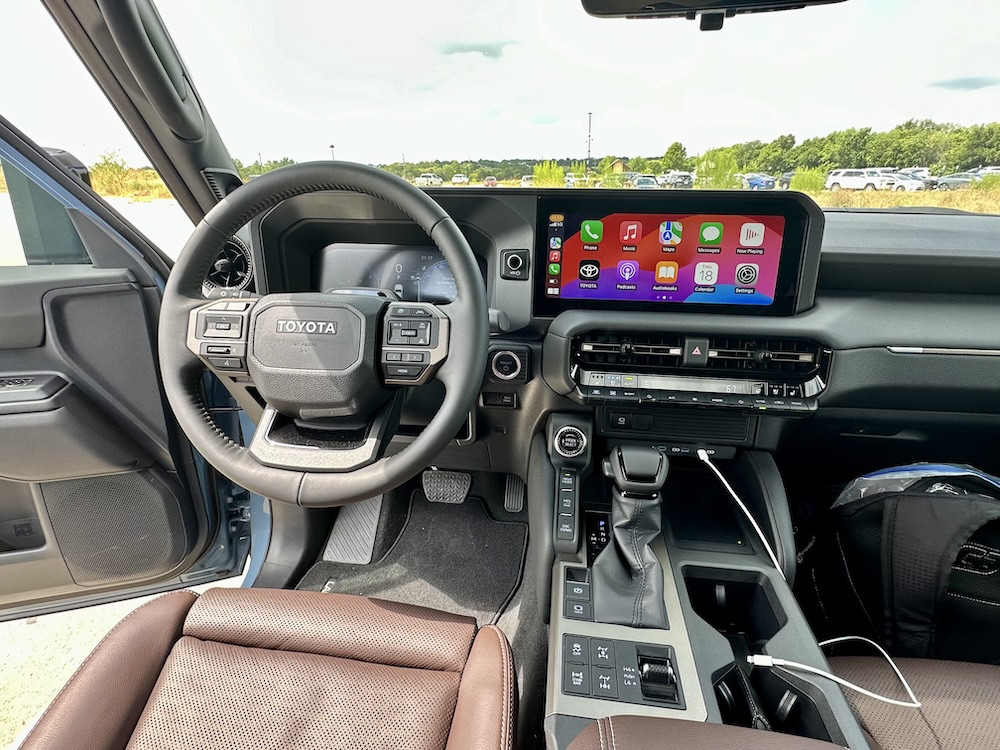 Front interior view of the Land Cruiser Premium, showing the dashboard, steering wheel, and infotainment system, emphasizing a blend of ruggedness and modern amenities.