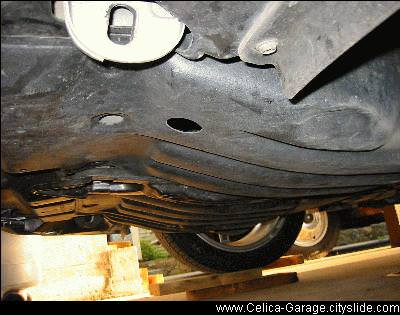 alt text: Engine bay of a 2002 Toyota Celica with the plastic engine cover removed, exposing the transmission