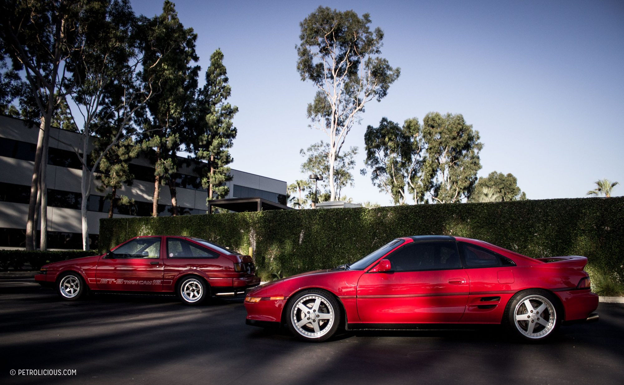 A red MR2 Turbo with its T-tops removed, parked in a scenic location.