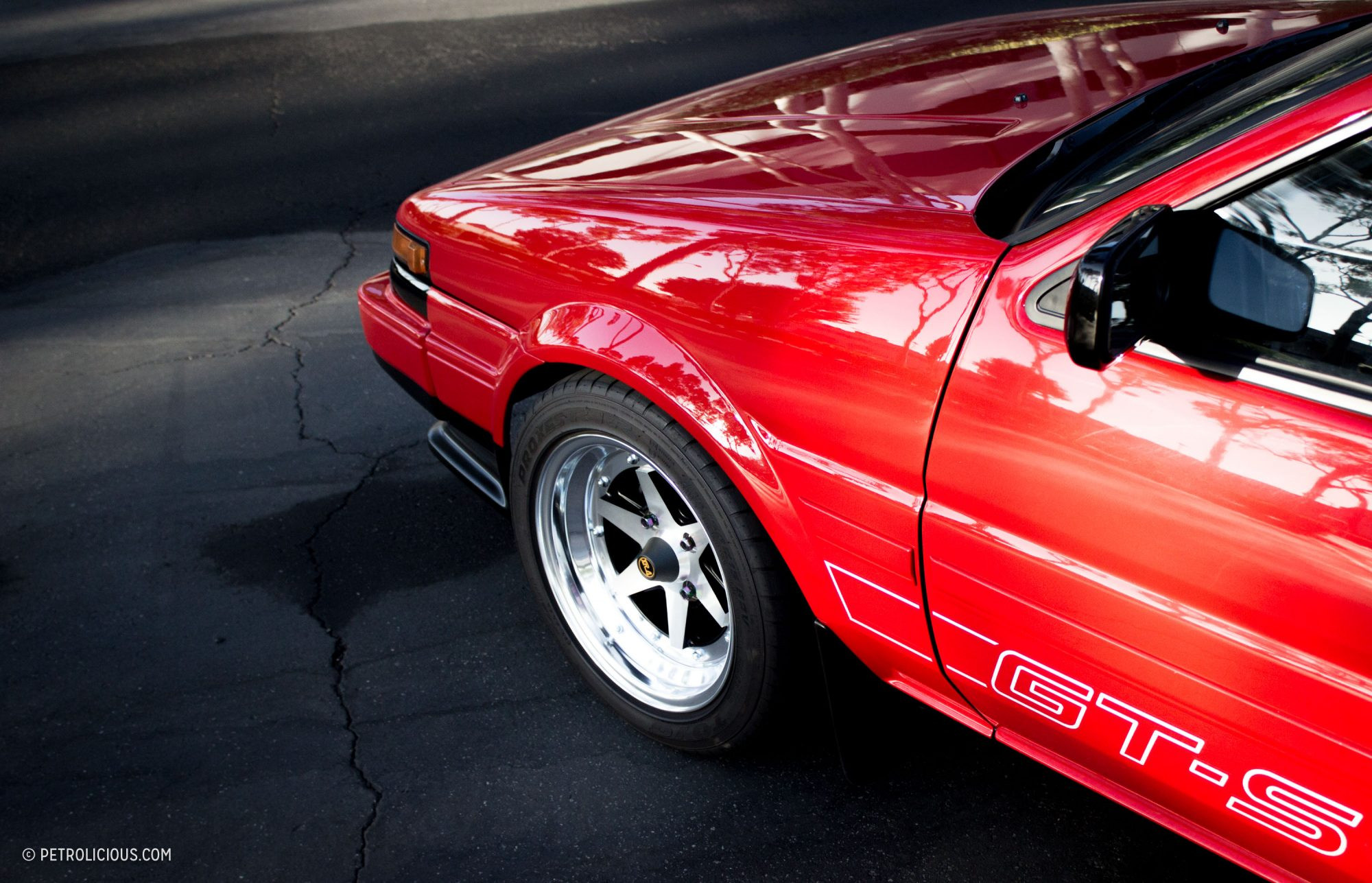 The engine bay of a red AE86, showcasing its meticulously maintained 4A-GE engine.