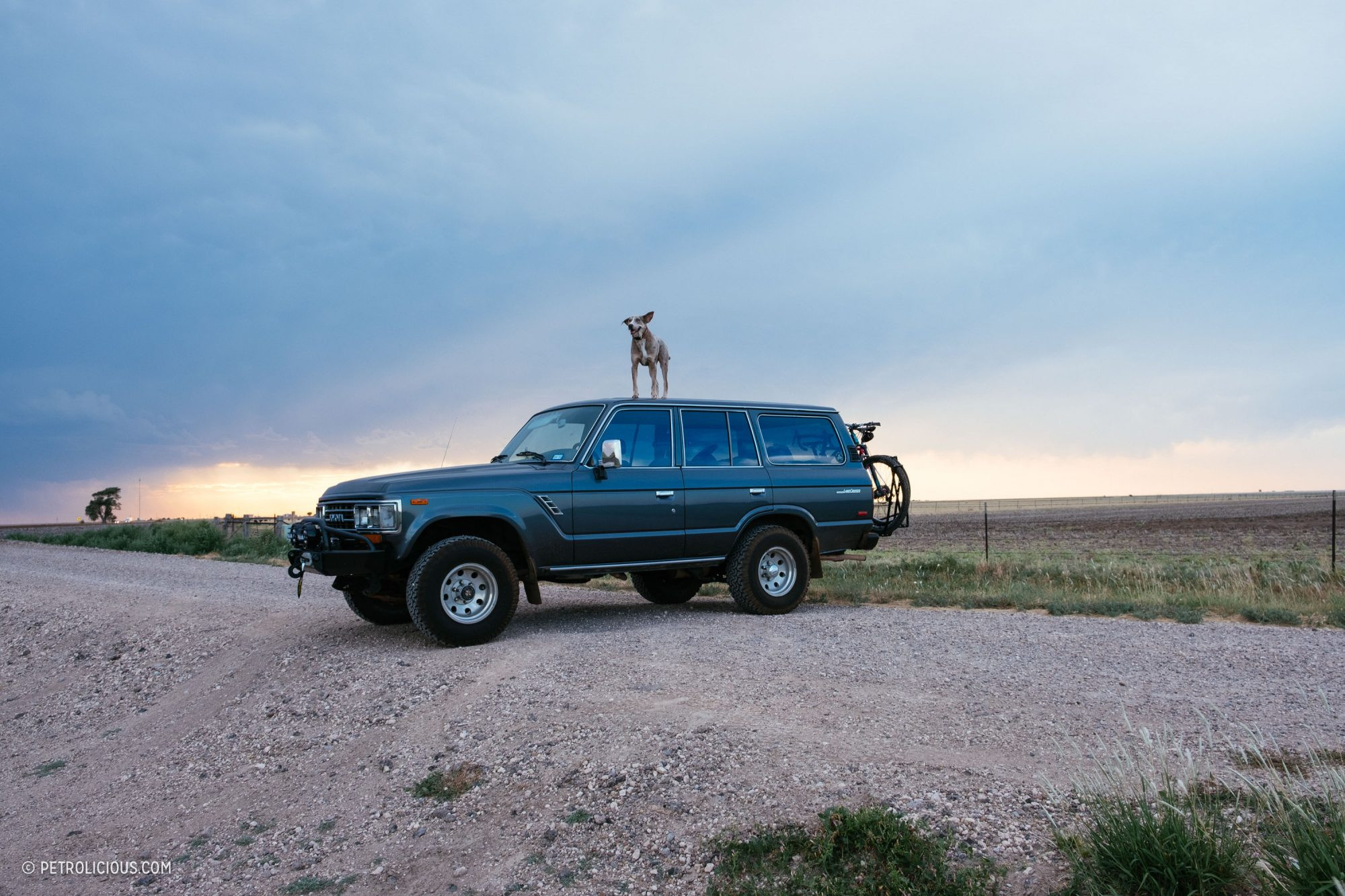 An old Toyota Land Cruiser driving on a red dirt road in rural Texas