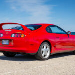 A sleek, red 1995 Toyota Supra Turbo with a six-speed manual transmission parked outdoors, emphasizing its iconic design and appeal
