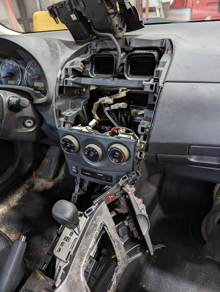 2013 Toyota Corolla center console disassembled to reach a rat's nest, emphasizing the importance of interior maintenance.