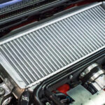 A close-up of a car radiator showing signs of wear and corrosion.