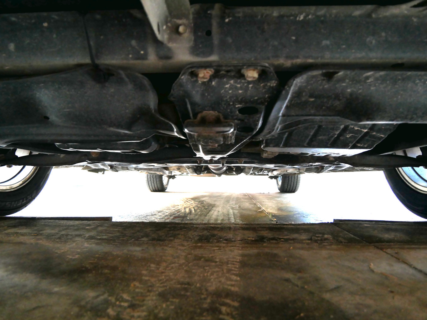 Looking underneath 2013 Toyota Corolla, inspecting for potential issues and wear.