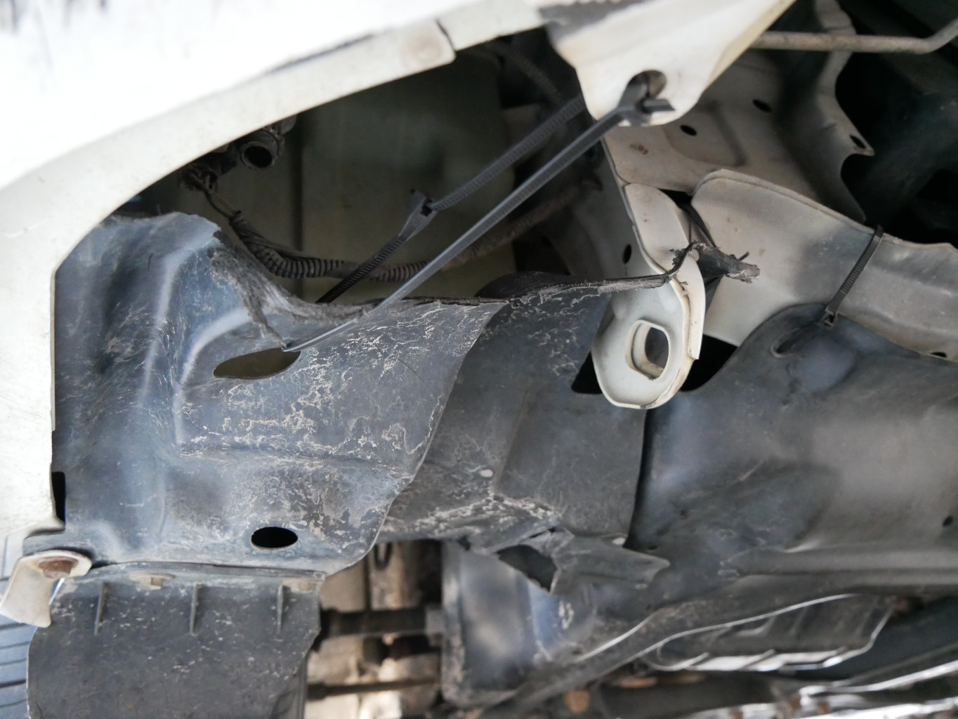 Front bumper and lower engine compartment covers held in place with zip ties on 2013 Toyota Corolla, showcasing proactive maintenance.